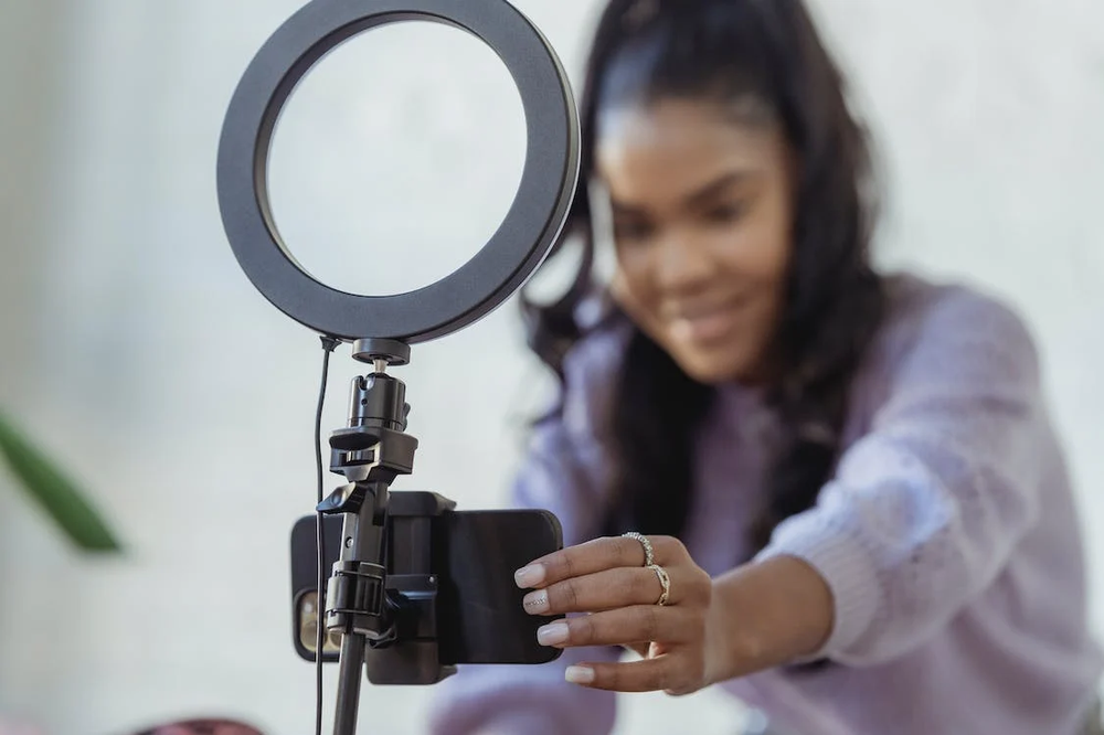 a person recording a video using a phone and ring light