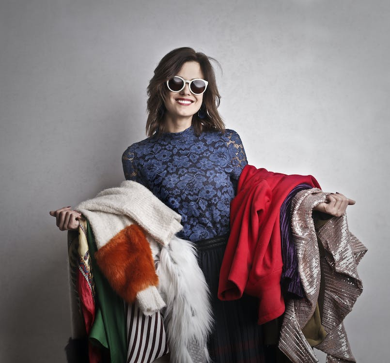 a woman with glasses carrying a bunch of clothes